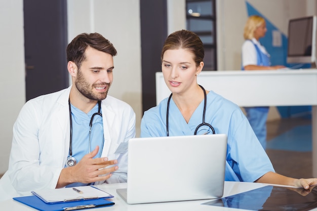 Doctor colleagues using laptop while discussing