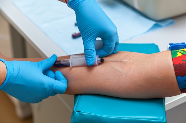 The doctor collects blood in a syringe, Nurse takes blood from the veins on the arm