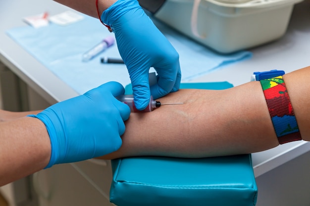 The doctor collects blood in a syringe, Nurse takes blood from the veins on the arm