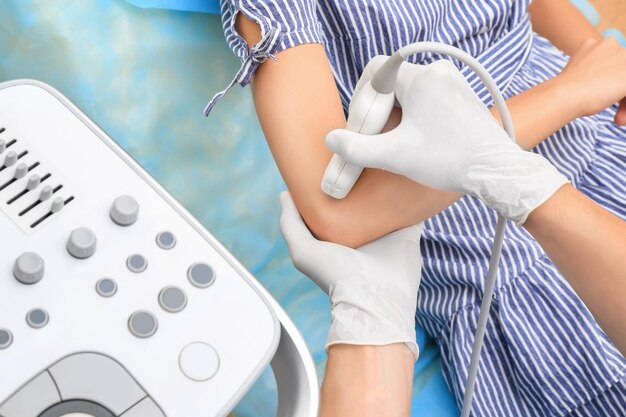 Doctor conducting ultrasound examination of patient's elbow in clinic