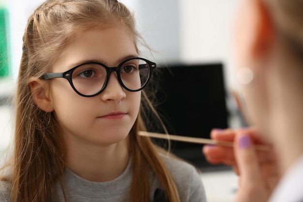 Doctor conducts medical examination of red sore throat of little girl