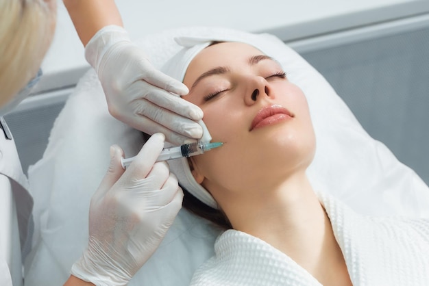 The doctor cosmetologist makes the rejuvenating facial injections procedure for tightening and