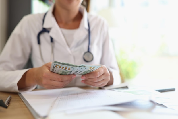 Doctor counts money in her hands in medical clinic