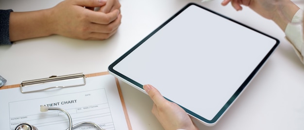 Doctor diagnose patient with blank screen tablet, patient chart and stethoscope in examination room