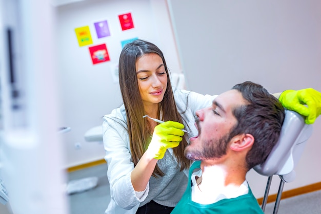 Photo doctor doing dental treatment on man's teeth in the dentists chair. 