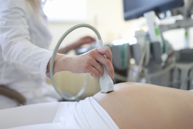 Photo doctor doing ultrasound examination of pregnant woman patient in clinic closeup