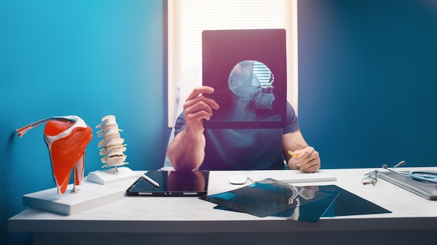 Doctor examines the x-ray and mri of head skull in the office. Health care concept