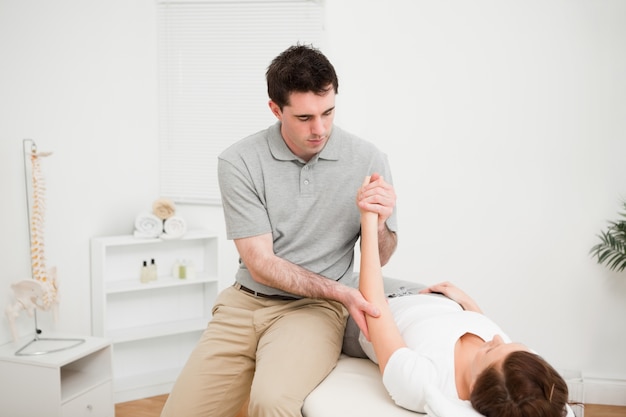 Doctor examining the arm of his patient while touching his elbow