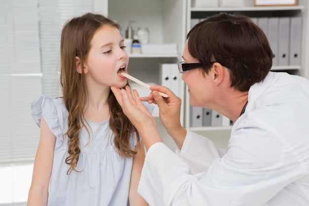 Doctor examining little girl mouth  