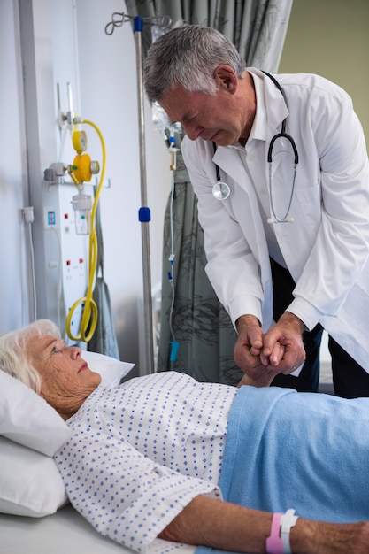 Doctor examining senior patient in ward