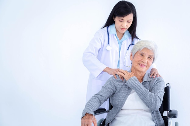 Doctor examining the shoulder and arm of asian senior old older woman sitting in wheelchair with happy.