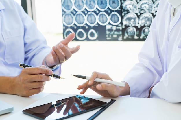 Doctor explaining consultant with x-ray films in consulting room