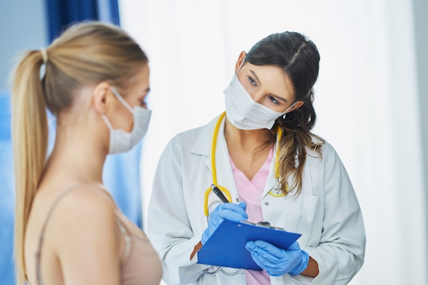 doctor explaining diagnosis to her female patient wearing a mask