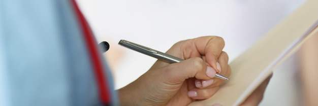 Doctor filling out patient medical documents with ballpoint pen in ward closeup health