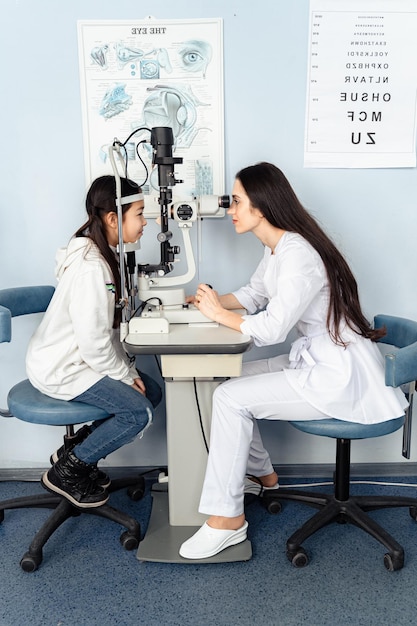 A doctor and a girl are looking at a microscope looks at an eye exam with a doctor