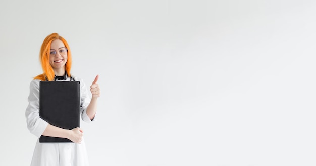 A doctor girl with red hair on a white background with a laptop in her hands