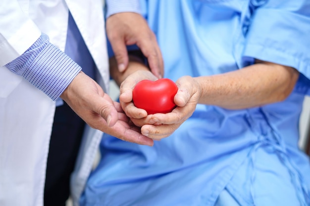 Doctor give red heart to Asian senior woman patient.