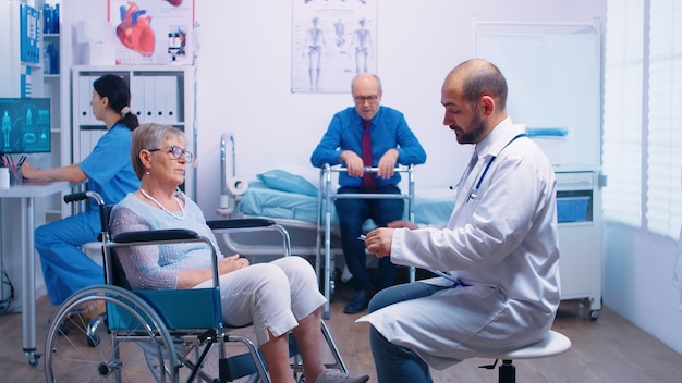 Doctor giving medical consultation in recovery clinic for senior retired disabled woman in wheelchair. Medical medicine health care supoprt and assistance treatment for elderly care assistance