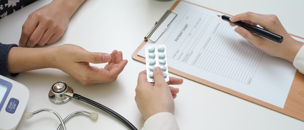 Doctor giving pills to patient while looking information on medical record