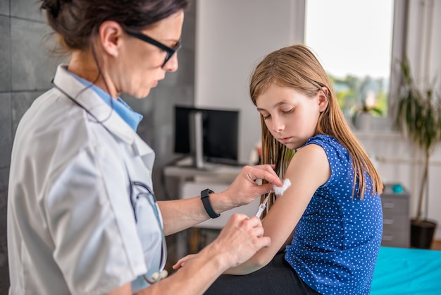 Doctor giving a young girl a vaccine shot