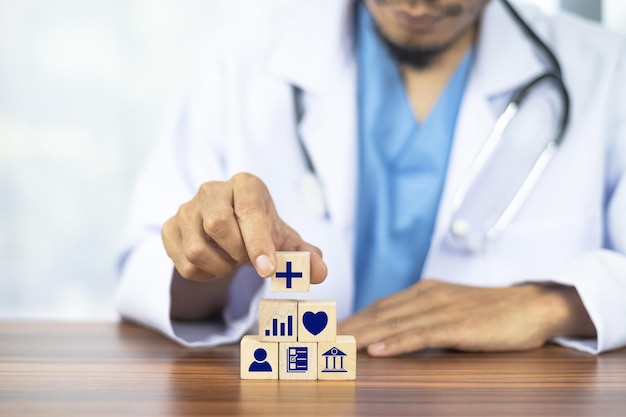 Doctor hand arranging wood block stacking with icon healthcare medical Insurance for your health concept