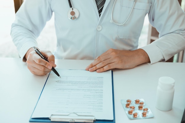 Doctor hand holding pen writing patient history list on note pad and talking to the patient about medication and treatment