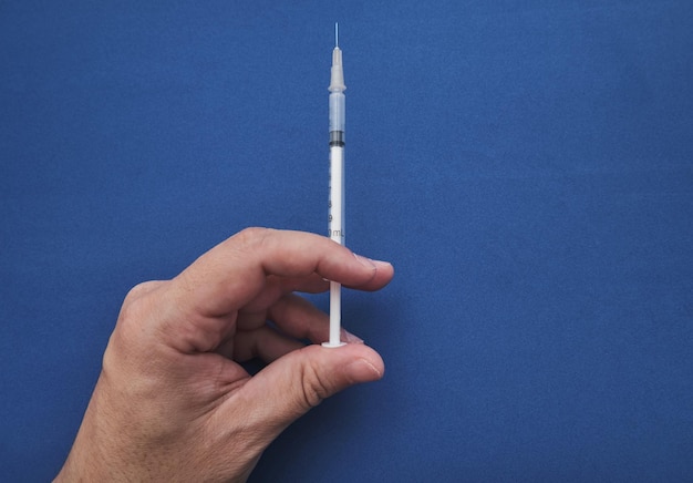 Doctor hand holding syringe to vaccinate with blue background and copy space