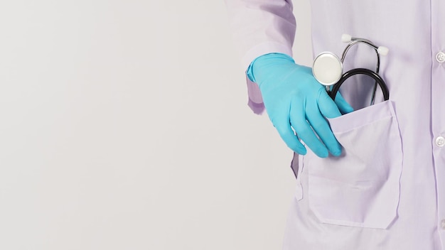 Doctor hand and stethoscope Hand wear the blue medical glove and a long sleeve gown on white