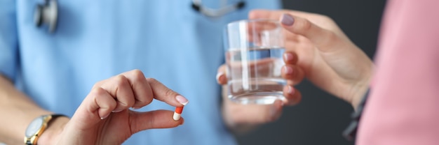 Doctor hands the patient pill and glass of water.