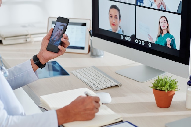 Doctor having video call with sick patient when having online conference with colleagues that help him to diagnose disease