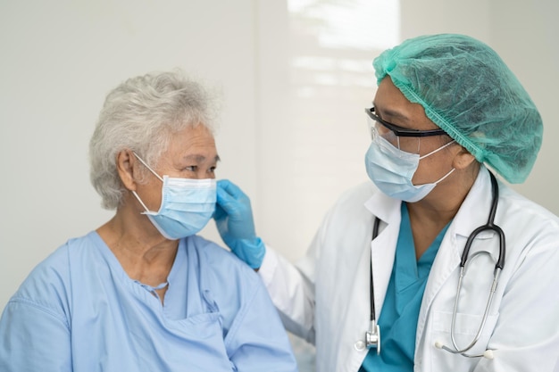 Doctor help Asian senior or elderly old lady woman patient wearing a face mask in hospital for protect safety infection and kill Covid19 Coronavirus