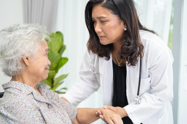 Doctor help and care Asian senior or elderly old lady woman patient sitting on wheelchair at nursing hospital ward healthy strong medical concept