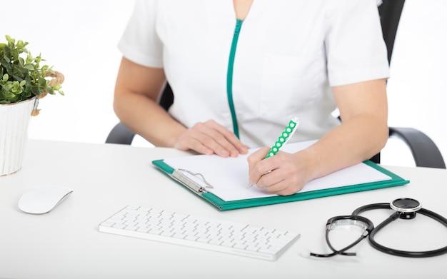 Doctor at his desk, writing on a document holder