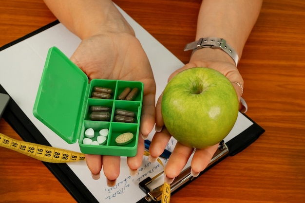 Doctor holding apple or dietary food supplement pills