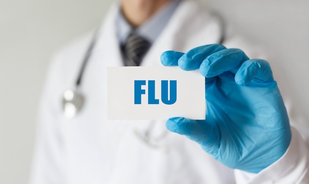 Doctor holding a card with text FLU , medical concept