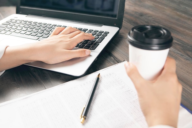 Doctor holding coffee in front of laptop