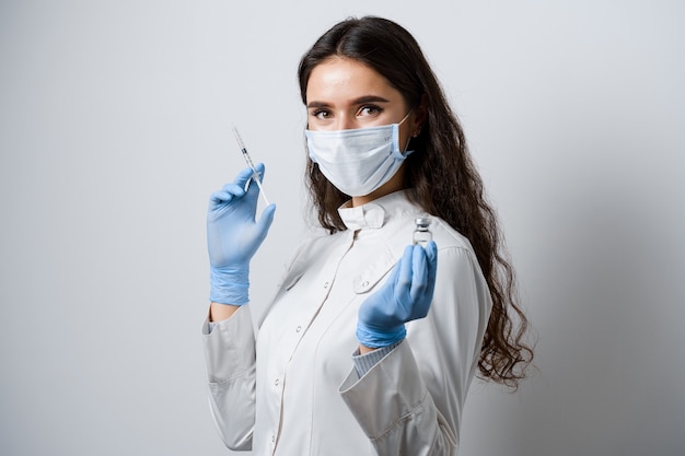 Doctor holding coronavirus vaccine. Attractive girl in medical gloves with syringe and medication