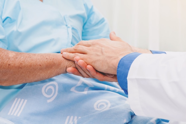 Doctor holding elderly person hand with care in hospital.healthcare and medicine