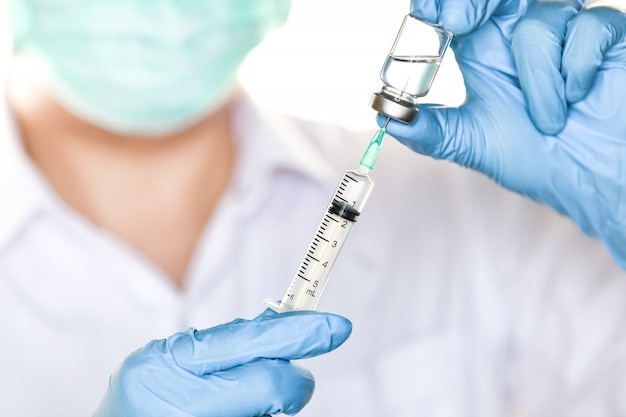 Doctor holding flu, measles injection vaccine and  syringe with needle for baby vaccination 