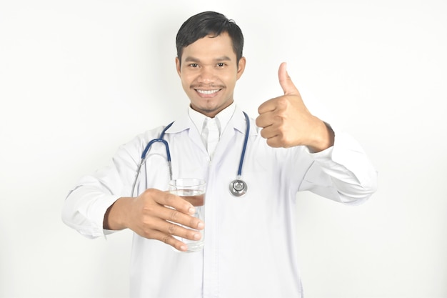 Doctor holding glass water and hand showing thumbs up on white background