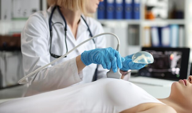 Doctor holding implant and doing ultrasound examination of woman breasts closeup