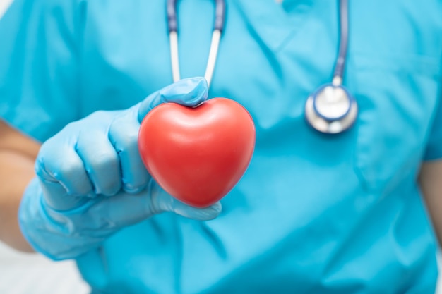 Doctor holding a red heart in hospital ward healthy strong medical concept