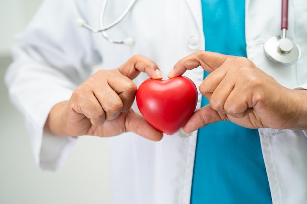 Doctor holding a red heart in hospital ward healthy strong medical concept