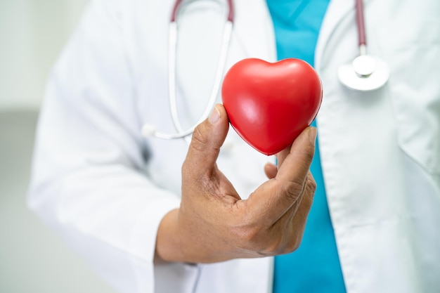 Doctor holding a red heart in hospital ward healthy strong medical concept