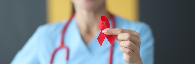 Doctor holding red ribbon in his hands closeup