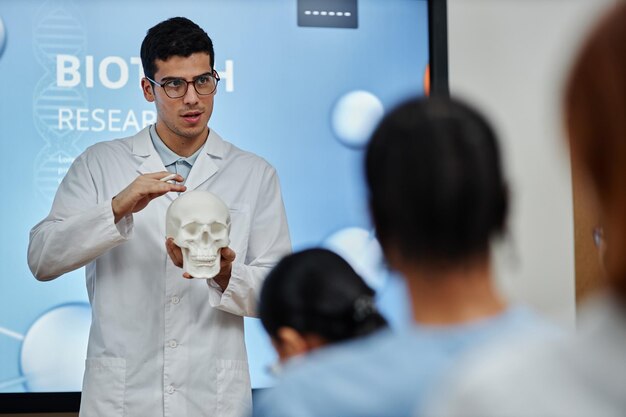 Doctor holding skull model during lecture or seminar in med college