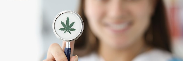 Doctor holding stethoscope with drawn marijuana leaf closeup