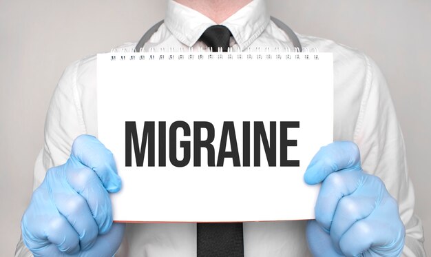 Doctor holding the word MIGRAINE on white paper notepad