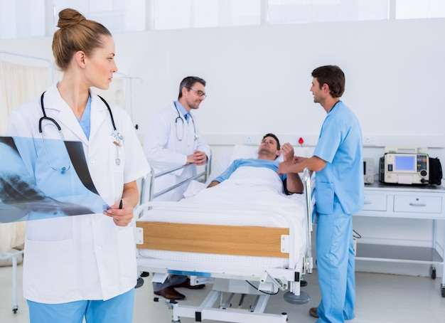 Doctor holding x-ray with colleagues and patient in hospital