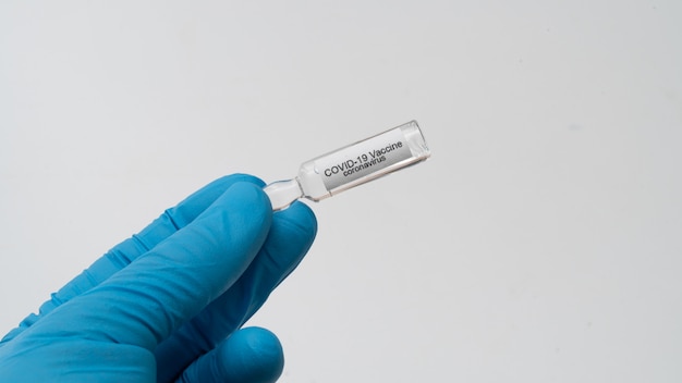 Doctor holds COVID 19 Coronavirus vaccine in his hand, infected blood sample in the sample tube, Vaccine and syringe injection It use for prevention, immunization and treatment from COVID-19